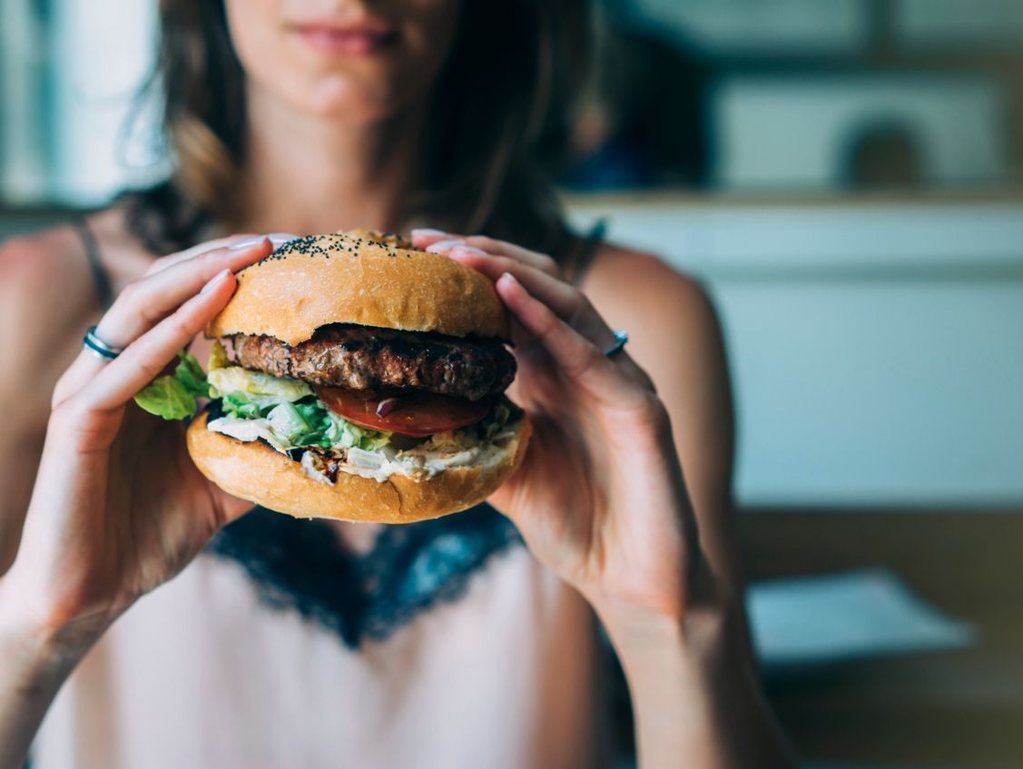 chica borrosa con hamburguesa en manos